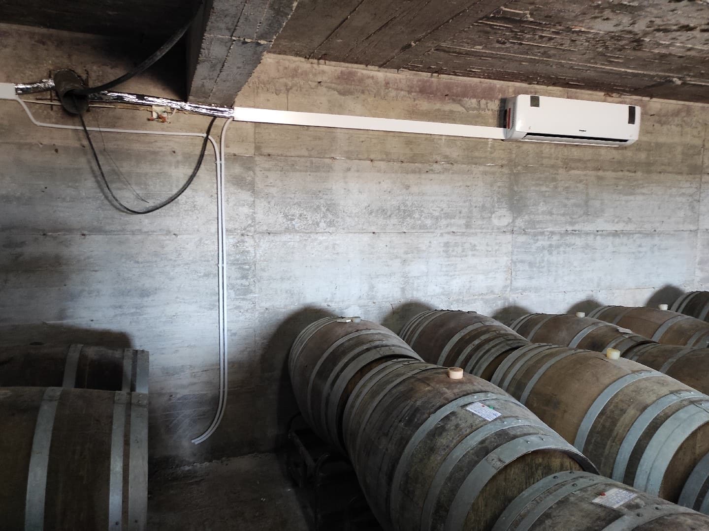 Ar condicionado instalado numa adega de vinhos, entre barricas de carvalho